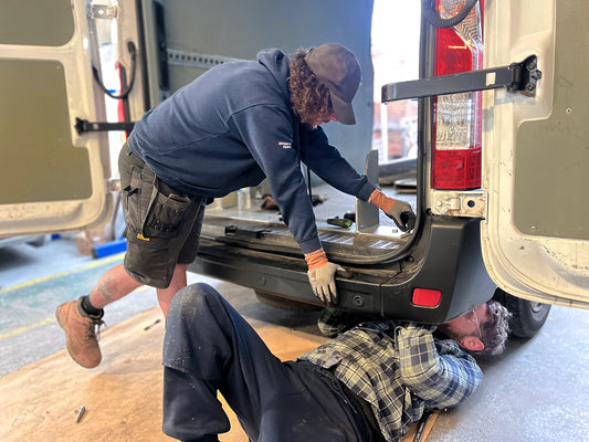 Two installers fitting a fixed folding van ramp into a van.